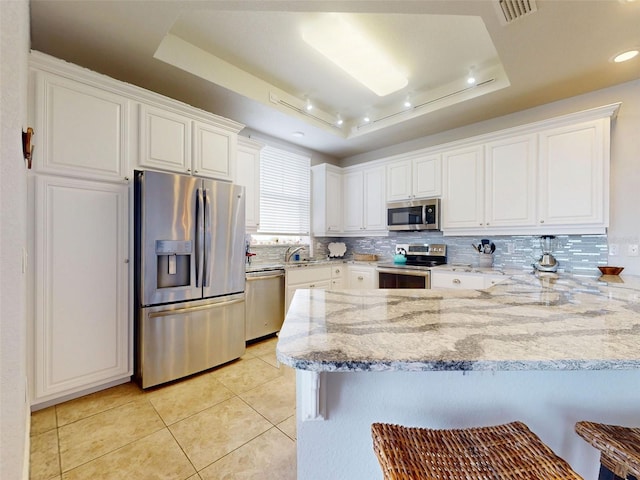 5 Riverwalk Dr Unit 601, New Smyrna Beach, FL 32169 - kitchen featuring stainless steel appliances, a raised ceiling, a peninsula, light tile patterned floors, and decorative backsplash