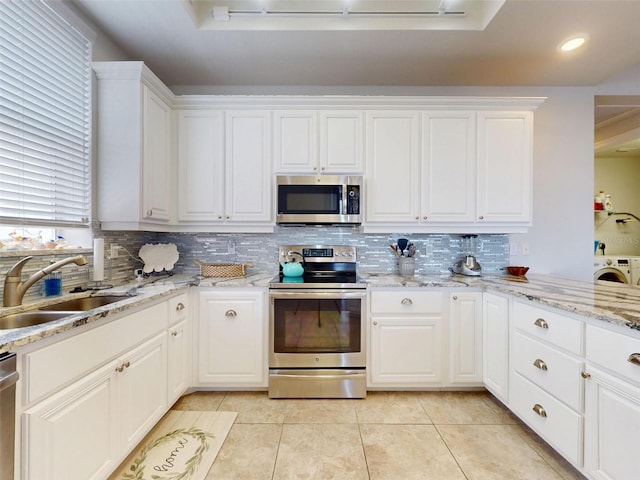 5 Riverwalk Dr Unit 601, New Smyrna Beach, FL 32169 - kitchen with appliances with stainless steel finishes, a sink, washer / dryer, and tasteful backsplash