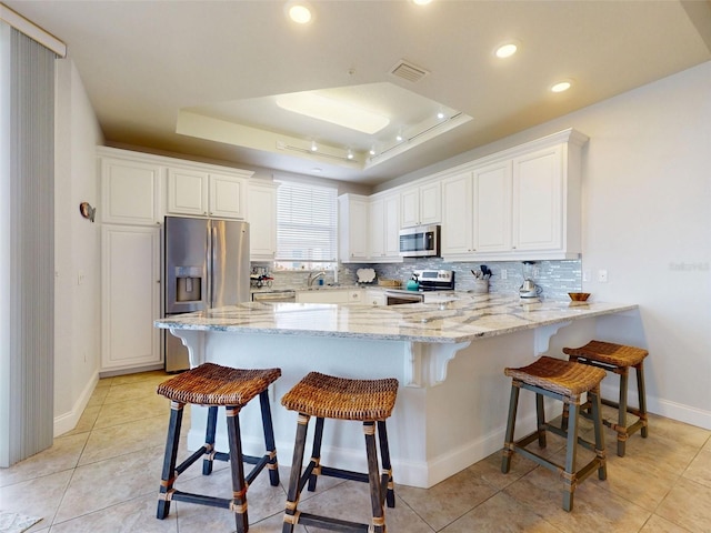 5 Riverwalk Dr Unit 601, New Smyrna Beach, FL 32169 - kitchen with appliances with stainless steel finishes, a peninsula, a raised ceiling, backsplash, and recessed lighting