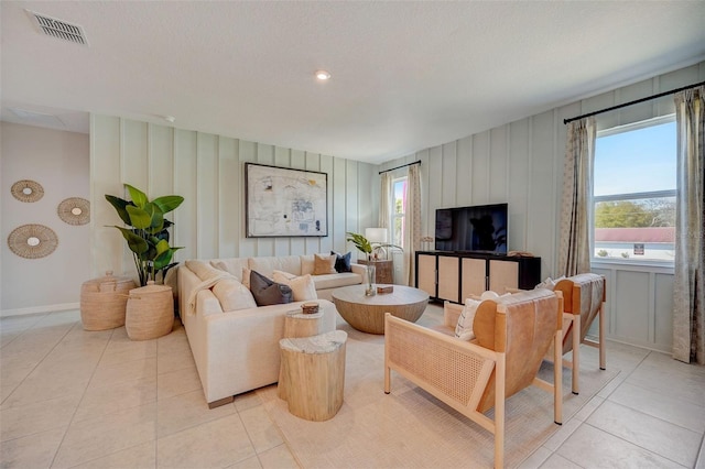 living room featuring light tile patterned floors, baseboards, and visible vents