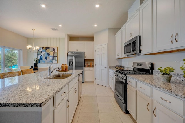 kitchen featuring a sink, stainless steel appliances, an island with sink, a chandelier, and white cabinetry