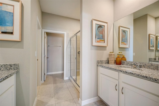full bathroom featuring a stall shower, vanity, baseboards, and tile patterned floors
