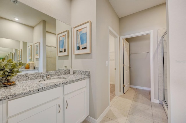bathroom with a stall shower, vanity, a spacious closet, and tile patterned floors