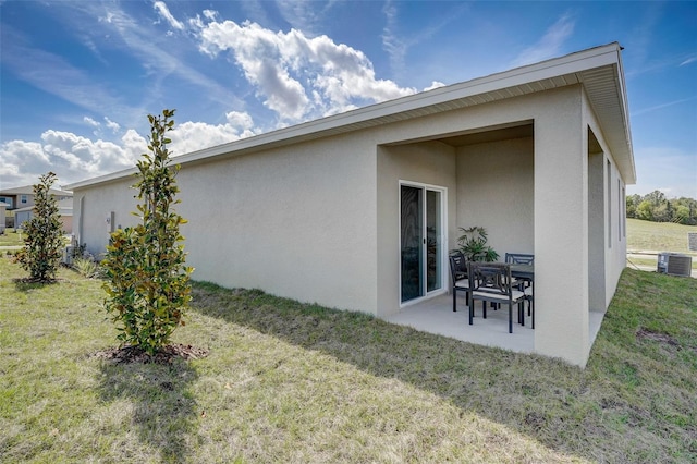 back of property featuring central air condition unit, a patio area, stucco siding, and a lawn