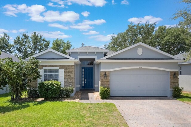 3436 Gerber Daisy Ln, Oviedo, FL 32766 - ranch-style home featuring decorative driveway, a garage, stucco siding, stone siding, and a front lawn