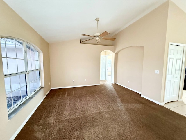 unfurnished room featuring lofted ceiling, carpet, baseboards, ceiling fan, and arched walkways