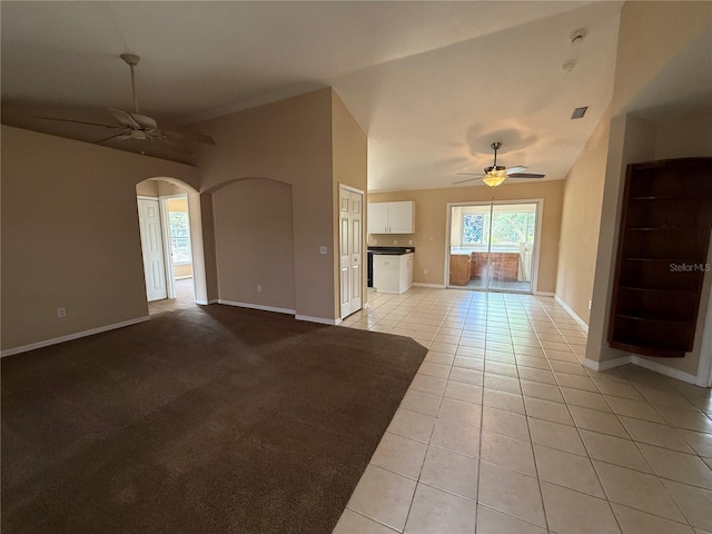 unfurnished living room featuring ceiling fan, arched walkways, baseboards, and light tile patterned floors