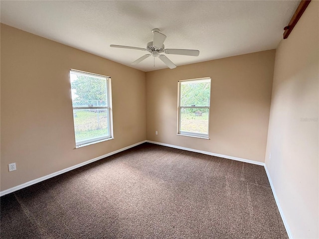 carpeted empty room featuring baseboards and a ceiling fan