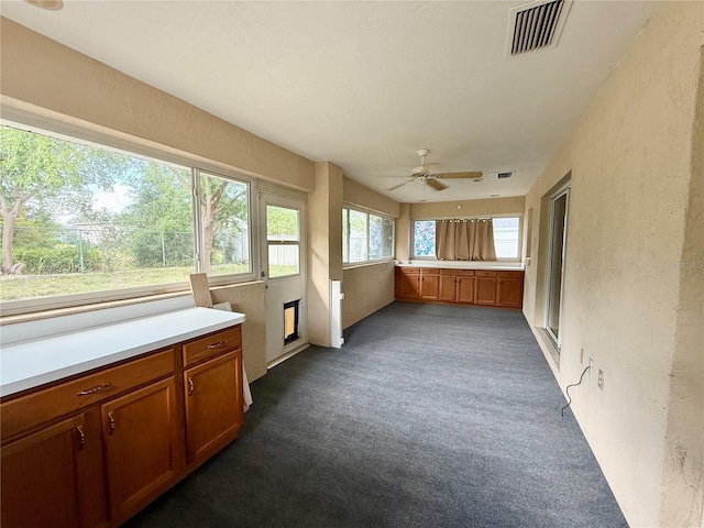 unfurnished sunroom with visible vents, carpet, and a textured wall