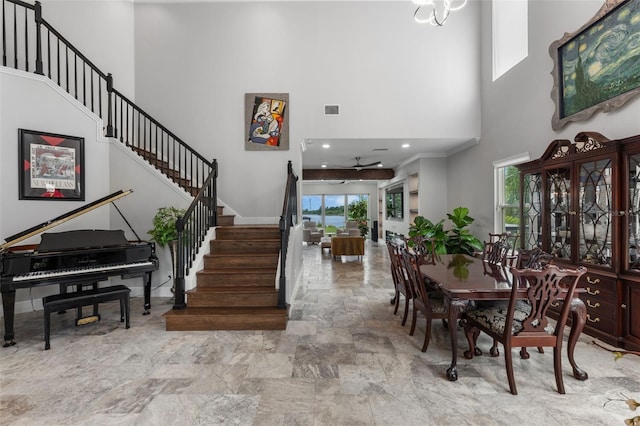 entrance foyer with a towering ceiling, stairway, stone finish flooring, ceiling fan, and baseboards