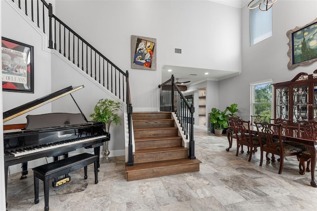 staircase with a high ceiling, stone finish flooring, baseboards, and ornamental molding