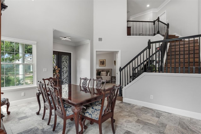dining space with a towering ceiling, baseboards, stairs, ornamental molding, and stone finish flooring