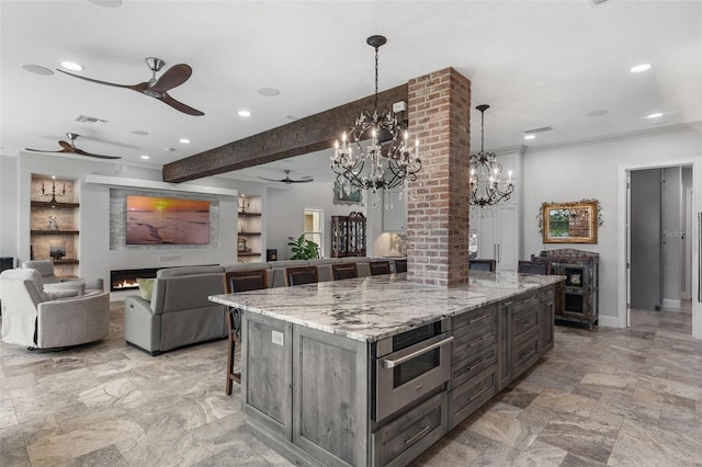 kitchen featuring a ceiling fan, a kitchen bar, a chandelier, a warm lit fireplace, and recessed lighting