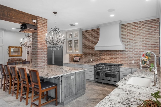 kitchen with high end appliances, premium range hood, a sink, a chandelier, and ornamental molding