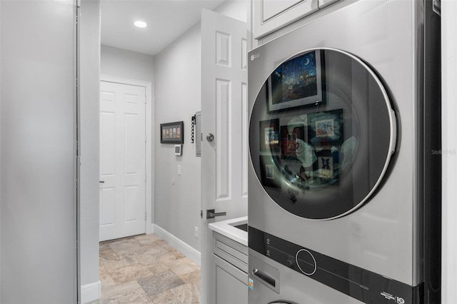washroom with stacked washer and clothes dryer, baseboards, light stone finish flooring, cabinet space, and recessed lighting