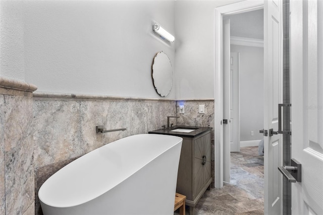 bathroom featuring crown molding, a freestanding bath, tile walls, vanity, and wainscoting
