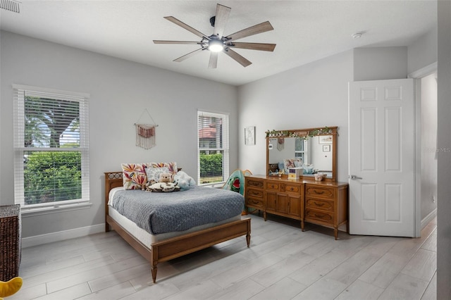 bedroom featuring multiple windows, light wood-style floors, and baseboards