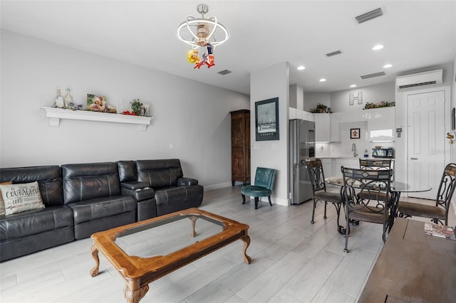 living area with a wall unit AC, recessed lighting, light wood-type flooring, a chandelier, and baseboards