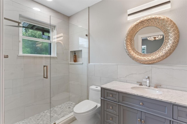full bath featuring toilet, a stall shower, tile walls, vanity, and a wainscoted wall