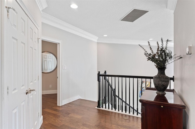 corridor with an upstairs landing, ornamental molding, wood finished floors, recessed lighting, and a textured ceiling