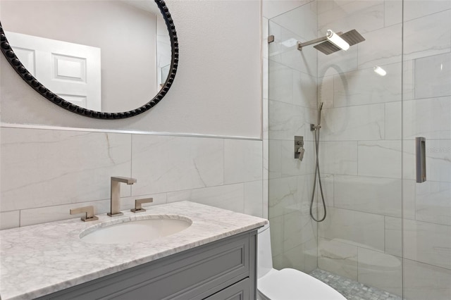 full bath with a shower stall, vanity, toilet, and tile walls