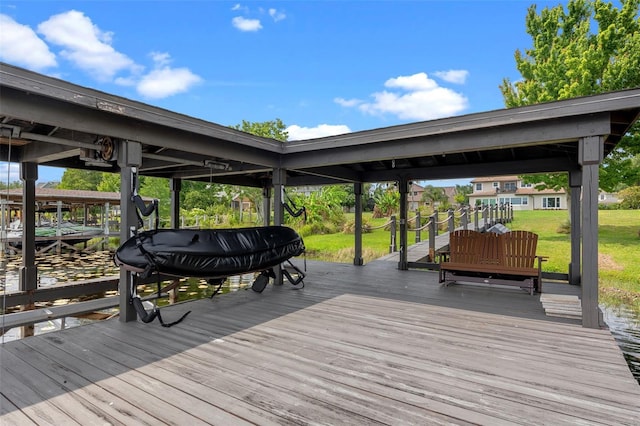 wooden deck with a lawn, boat lift, and a boat dock