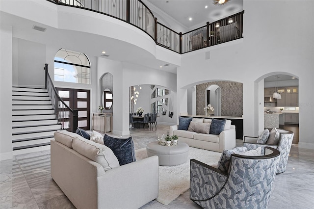 living room featuring arched walkways, marble tiled flooring, a high ceiling, baseboards, and stairway