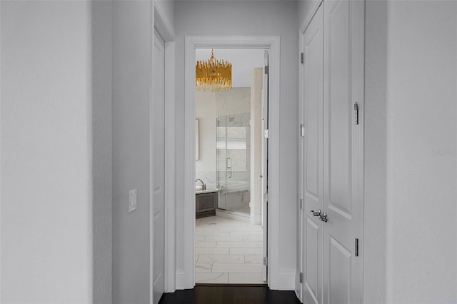 hallway featuring a chandelier and dark marble finish floors