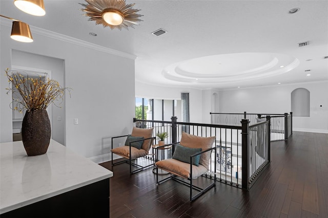 corridor featuring a raised ceiling, an upstairs landing, baseboards, dark wood-style flooring, and crown molding
