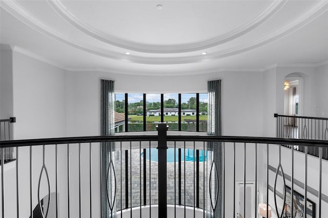 corridor featuring a tray ceiling, crown molding, recessed lighting, and arched walkways