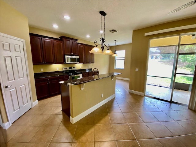 30732 Lipizzan Ter, Mount Dora, FL 32757 - kitchen featuring an island with sink, light tile patterned flooring, baseboards, and appliances with stainless steel finishes