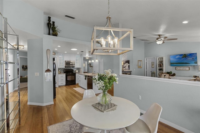 dining area with light wood finished floors, a chandelier, baseboards, ceiling fan, and recessed lighting