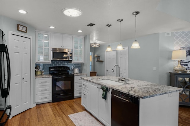 kitchen with black appliances, a sink, white cabinets, light stone countertops, and recessed lighting