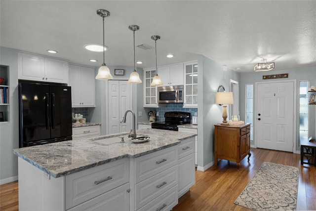 kitchen with black appliances, a sink, wood finished floors, tasteful backsplash, and recessed lighting