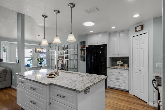kitchen featuring a sink, freestanding refrigerator, wood finished floors, white cabinetry, and recessed lighting
