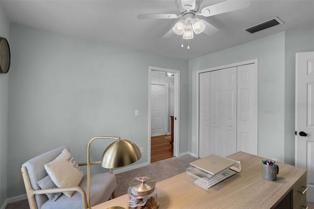 carpeted office space with ceiling fan and baseboards