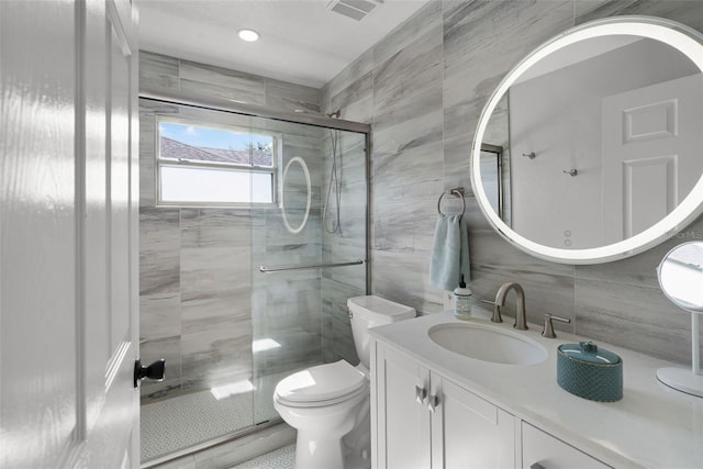 bathroom featuring tile walls, a shower stall, toilet, vanity, and decorative backsplash