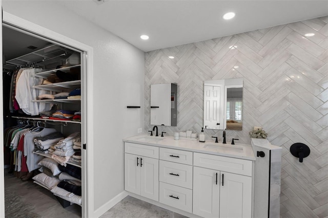 full bathroom featuring double vanity, a spacious closet, tasteful backsplash, recessed lighting, and baseboards