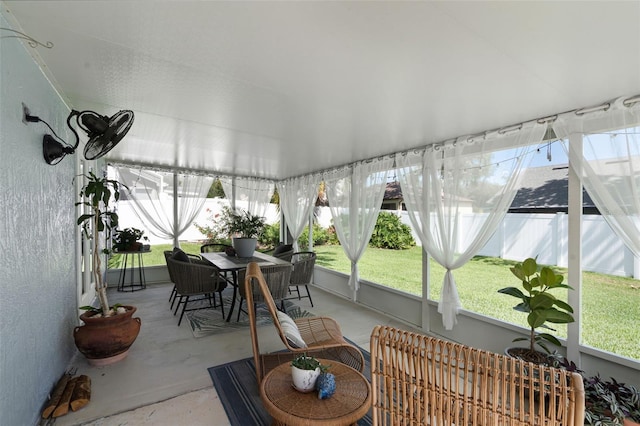 sunroom / solarium featuring outdoor dining area and concrete flooring