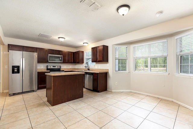 2320 Red Ember Rd, Oviedo, FL 32765 - kitchen with stainless steel appliances, dark brown cabinetry, a center island, light countertops, and a sink