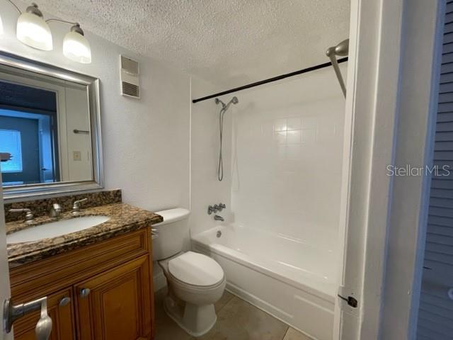 full bathroom featuring toilet, shower / bath combination, a textured ceiling, visible vents, and vanity