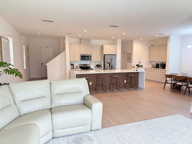 living area with recessed lighting, light wood finished floors, and visible vents