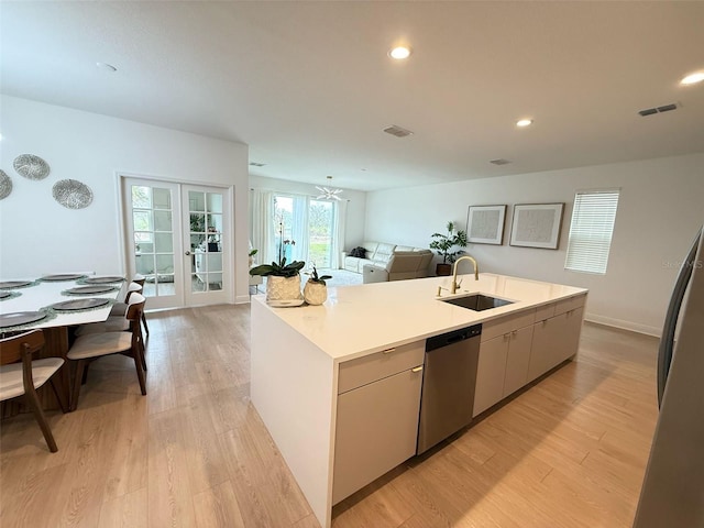 kitchen featuring french doors, an island with sink, a sink, stainless steel appliances, and visible vents