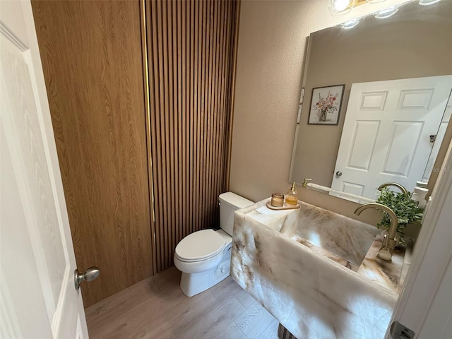 half bathroom featuring a sink, toilet, and wood finished floors