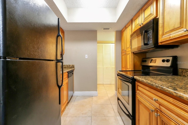4727 S Texas Ave Unit 4727C, Orlando, FL 32839 - kitchen featuring light tile patterned floors, brown cabinetry, visible vents, a raised ceiling, and black appliances
