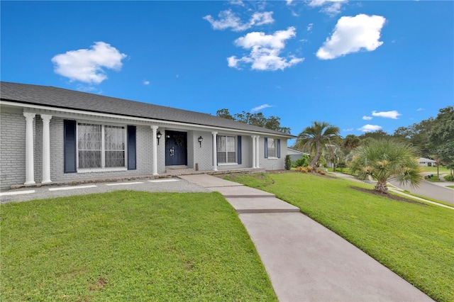 single story home featuring a porch, brick siding, and a front lawn