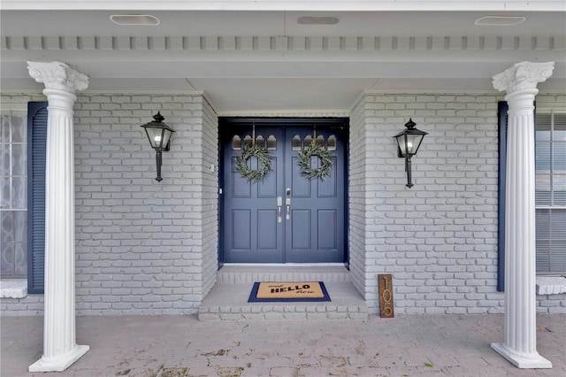 property entrance featuring covered porch and brick siding