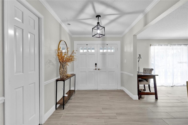 foyer entrance featuring a textured ceiling, baseboards, a chandelier, crown molding, and light wood-style floors