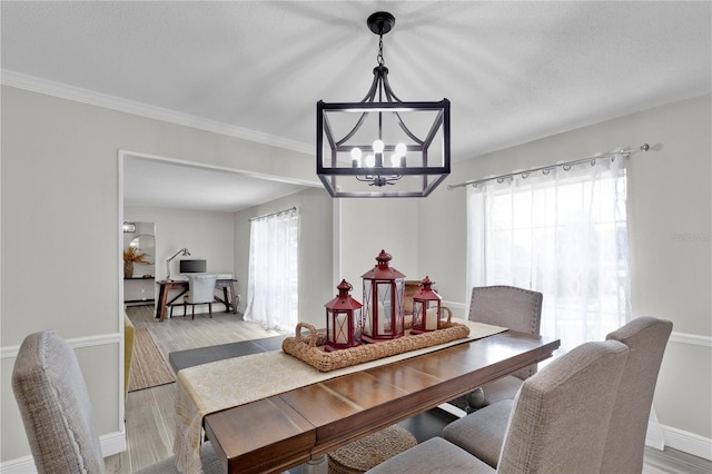 dining room with light wood-type flooring, baseboards, ornamental molding, and a notable chandelier