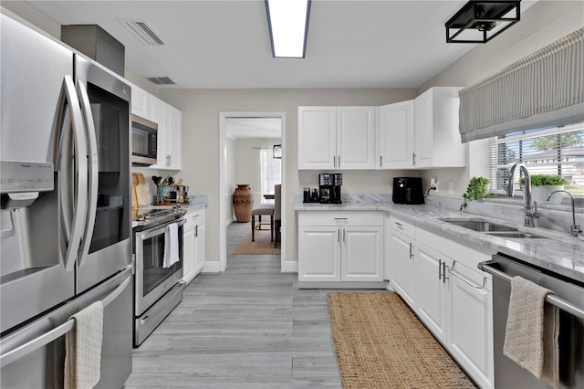 kitchen with light stone countertops, stainless steel appliances, visible vents, and a sink